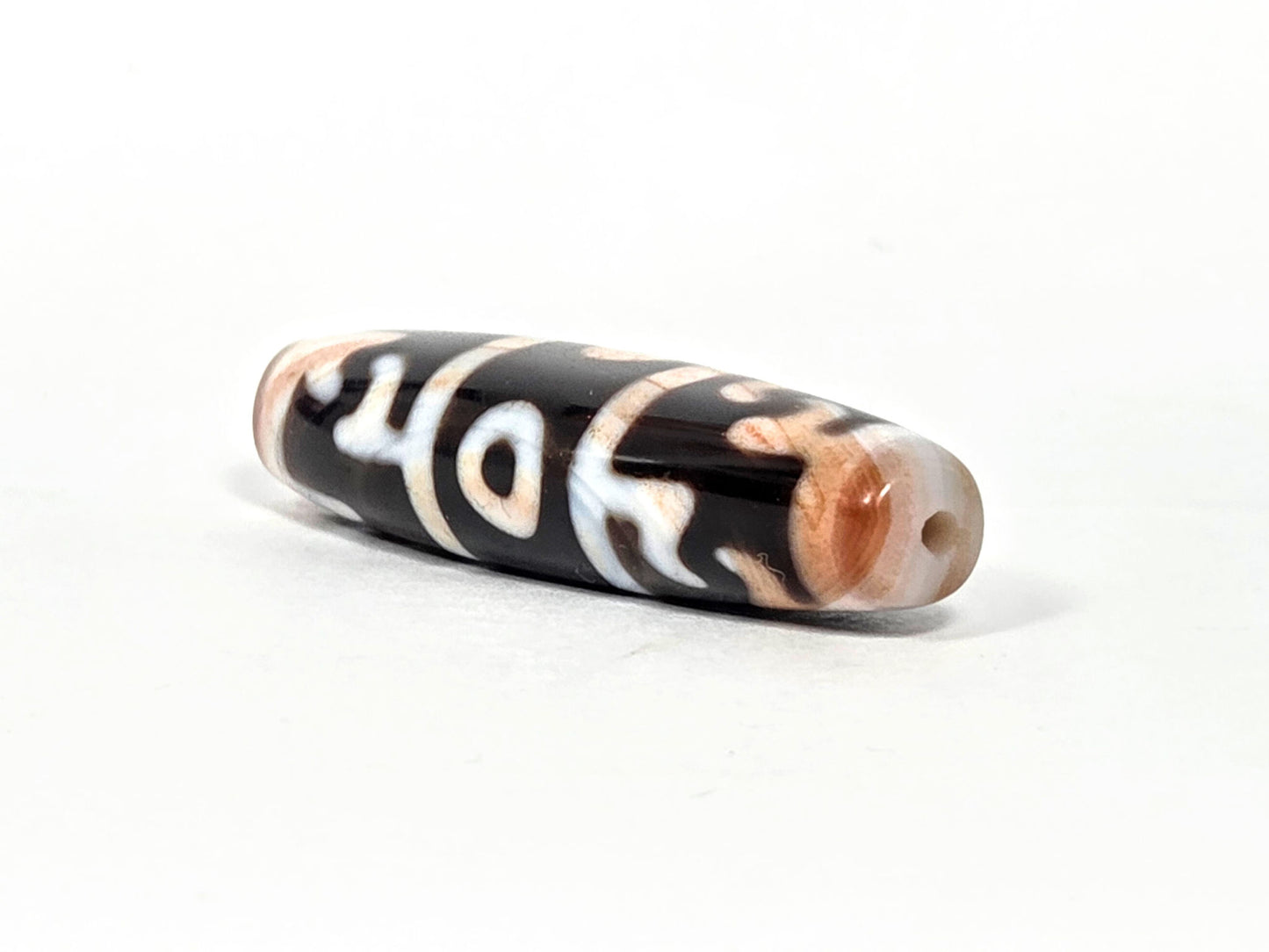 At-070626-GRRP3EBS angled drill-end view, warm peach-orange agate end cap, pitch-black body, unretouched