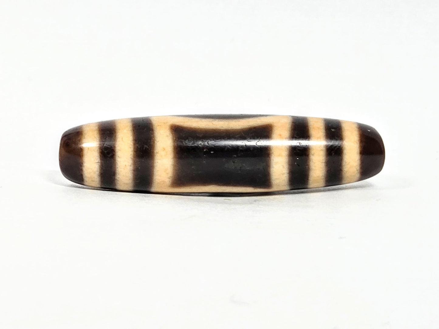 At-071326-HE opposite face C, angular trapezoidal oval reading, warm honey-cream patina on bar zones, unretouched