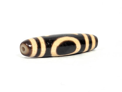 At-071326-HE rounded drill-hole end, warm brown-grey cap, second drill hole, cream oval motif on body, unretouched
