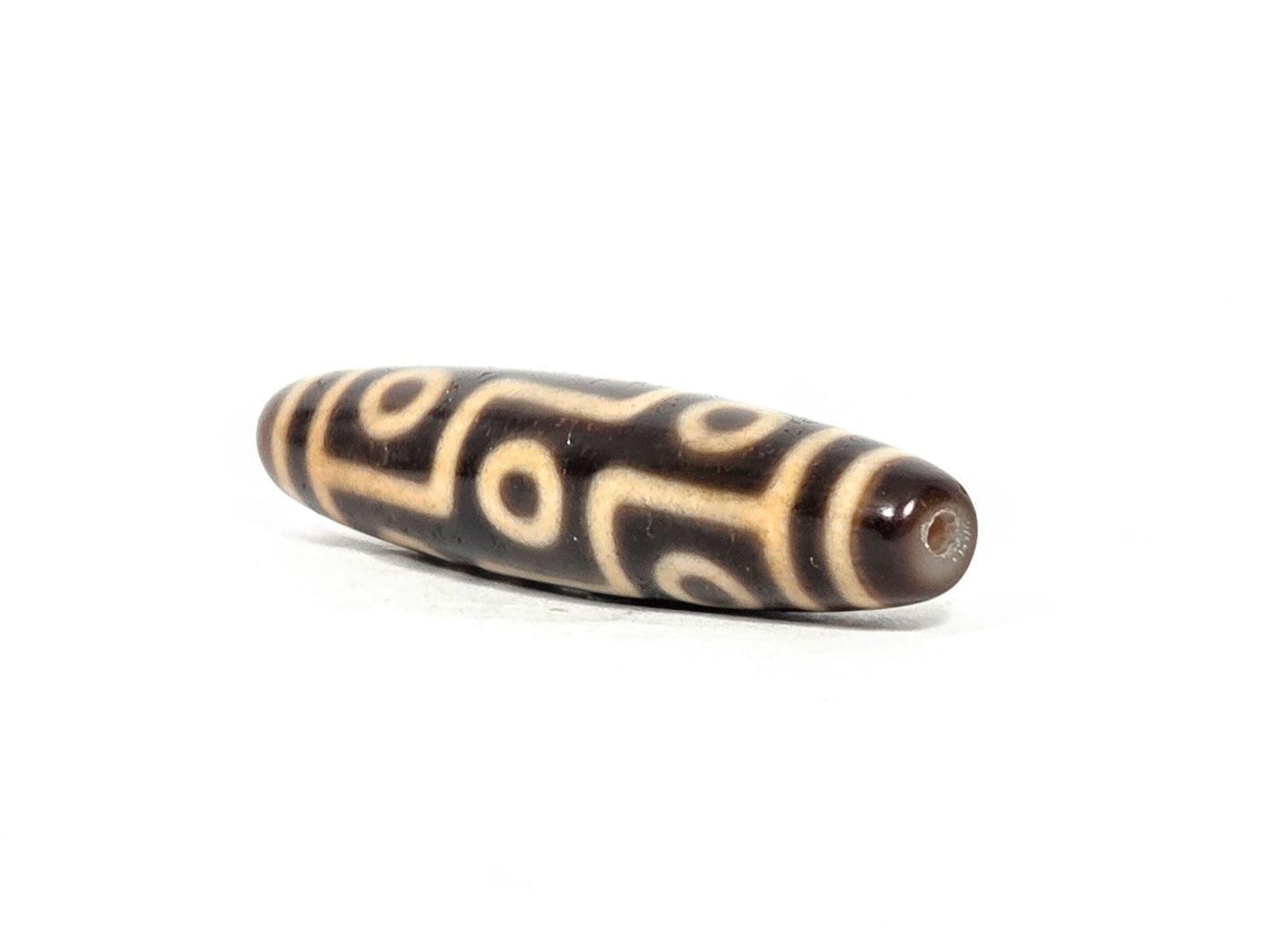 At-071326-9E three-quarter end, warm honey-brown end cap, small drill hole, full oval barrel profile visible, unretouched