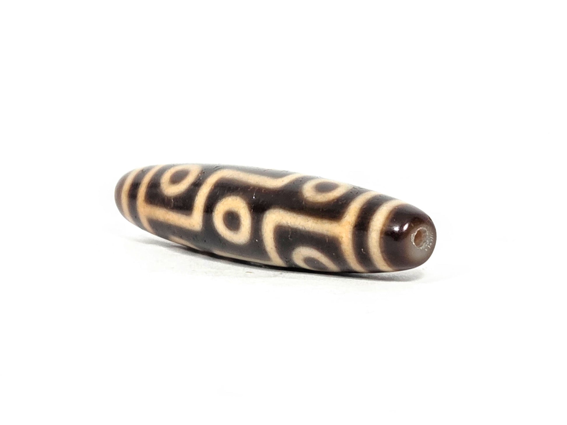 At-071326-9E three-quarter end, warm honey-brown end cap, small drill hole, full oval barrel profile visible, unretouched