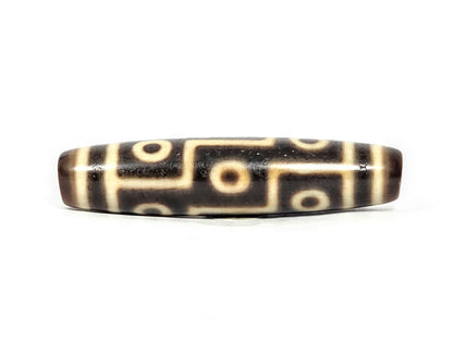 At-071126-9E6 face A, antique nine eye Tibetan dzi 54.8×12.6mm, very dark brown ground, cream motif lines, 300–500 yrs, unretouched