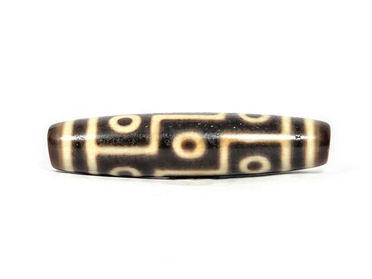 At-071126-9E6 face A, antique nine eye Tibetan dzi 54.8×12.6mm, very dark brown ground, cream motif lines, 300–500 yrs, unretouched