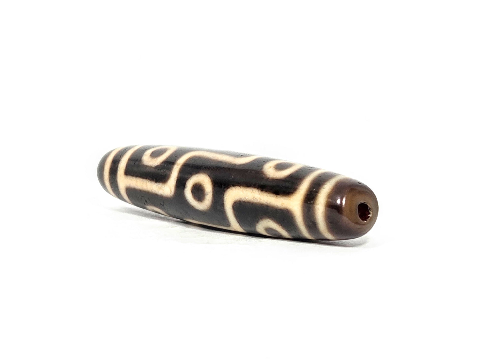 At-070826-9E antique nine eye dzi bead angled view right drill end warm reddish-brown end cap unretouched