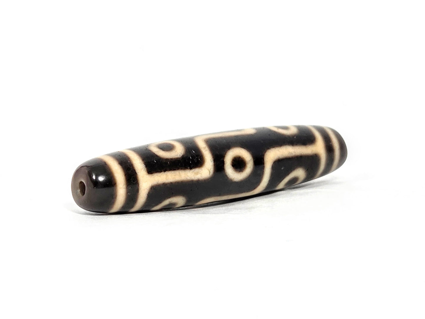 At-070826-9E antique nine eye dzi bead angled view left drill end warm reddish-brown end cap profile unretouched