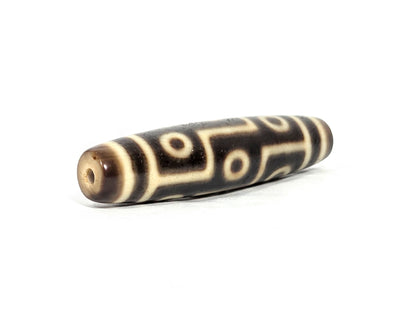 At-071126-9E6 opposite drill-hole end, warm cream-beige end cap, small clean hole, nine eye motif to end boundary, unretouched