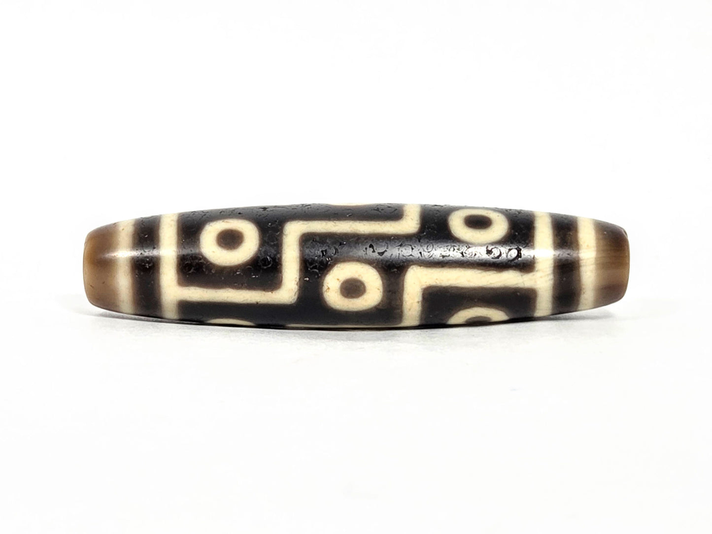 At-071126-9E7 face A, antique nine eye dzi 55.0×12.7mm, very deep dark brown agate, cool cream-white motif lines, unretouched