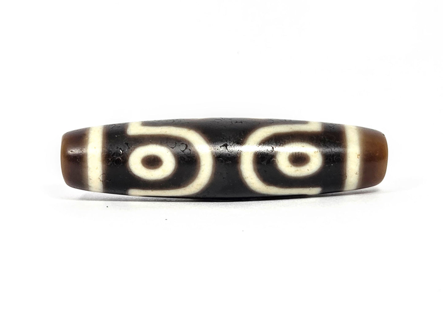 At-072226-7E Seven Eye face C — paired eyes with S-curve wave connectors, bold cream motif lines, unretouched. 