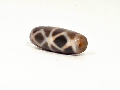 At-080926-6EDS2 antique Six Eye Diamond Spear dzi bead 33.0×11.5mm, angled drill-end view showing warm honey agate channel and diamond lines wrapping to end, unretouched