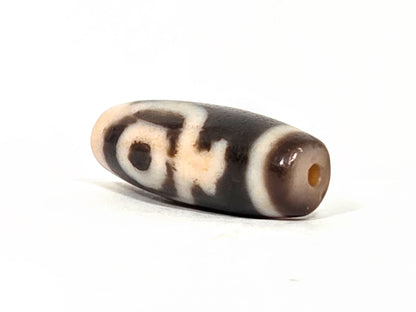 At-062226-2ETV2, end view showing peachy-cream end cap, drill hole intact, dark brown body, fusiform taper, unretouched
