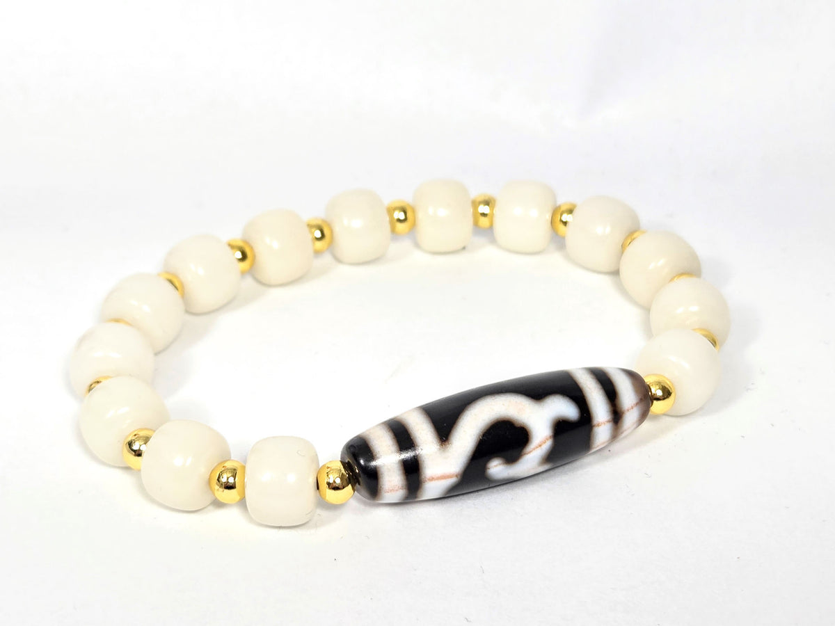 Black and white Dzi bead bracelet with wave motif, white Bodhi root beads, gold spacers, cinnabar bloodspots visible on elongated agate bead