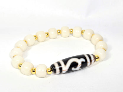 Black and white Dzi bead bracelet with wave motif, white Bodhi root beads, gold spacers, cinnabar bloodspots visible on elongated agate bead