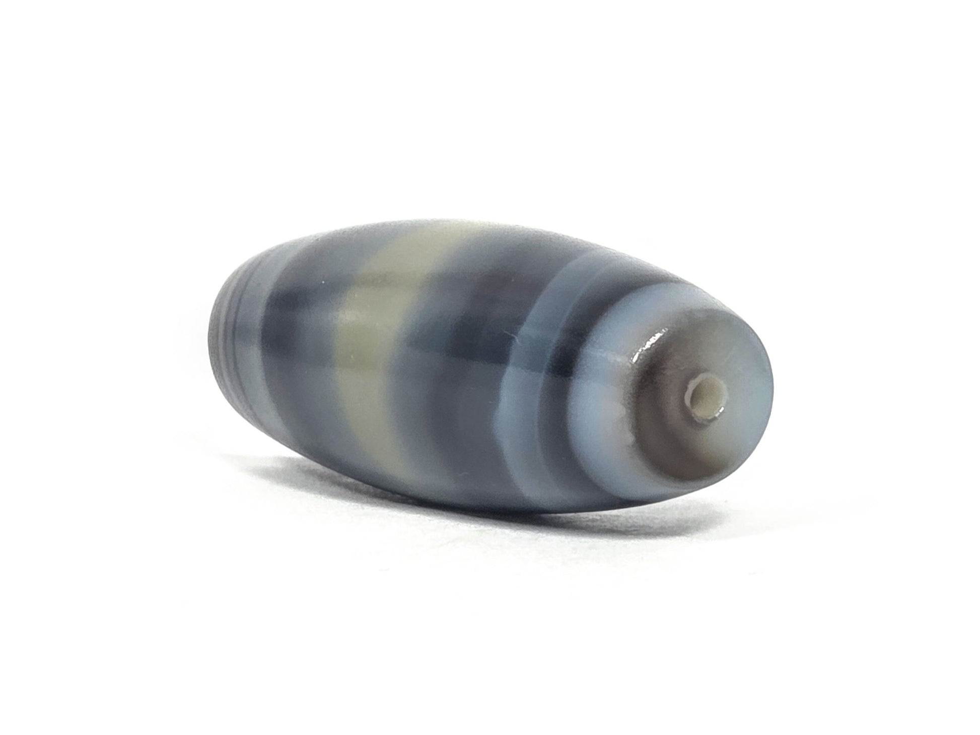 N-N-071426-1E4 end angle A — warm grey-brown end cap, small clean drill opening, banding wrap visible, unretouched.
