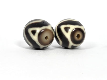 At-070626-TTW antique round Wave Tiger Tooth dzi pair, drill-end face view: Bead A cool grey-beige end cap, Bead B warm honey-brown end cap, unretouched