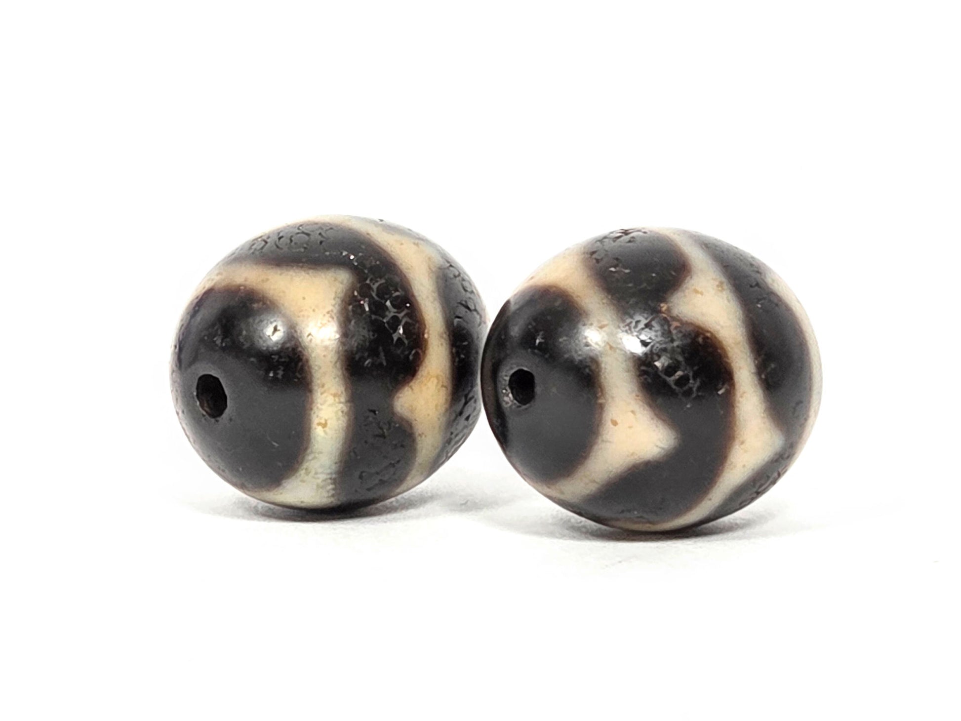V-060826-DWP2 opposite end pair, diamond lozenge resolution visible, pitch-black ground, sandy-cream, unretouched