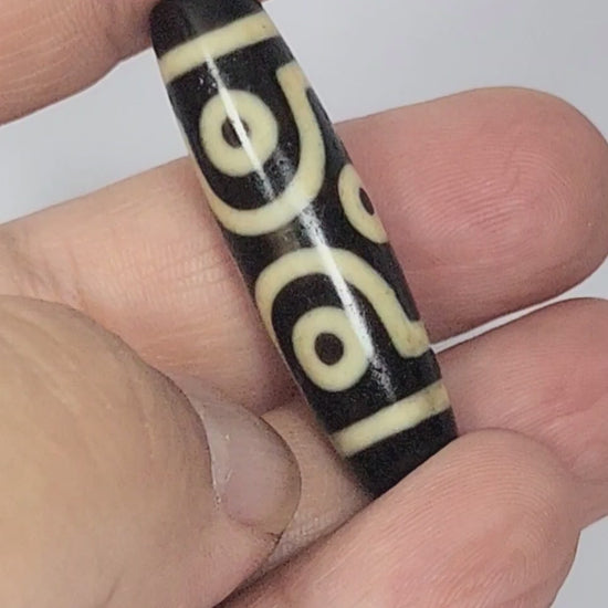 Video of antique Tibetan six eye dzi At-042925-6E2 rotating 360°, pitch-black agate, bold scroll paired eyes and diamond frame single eyes, 41.4mm × 11.4mm, unretouched footage