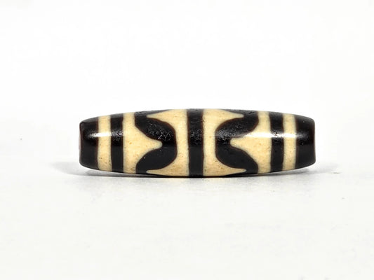 Antique Tibetan double wave dzi bead (AT-092826-DW), first lateral profile showing bold black double wave forms in three panels on cream-white agate ground, 41.1 mm, 200–400 years old