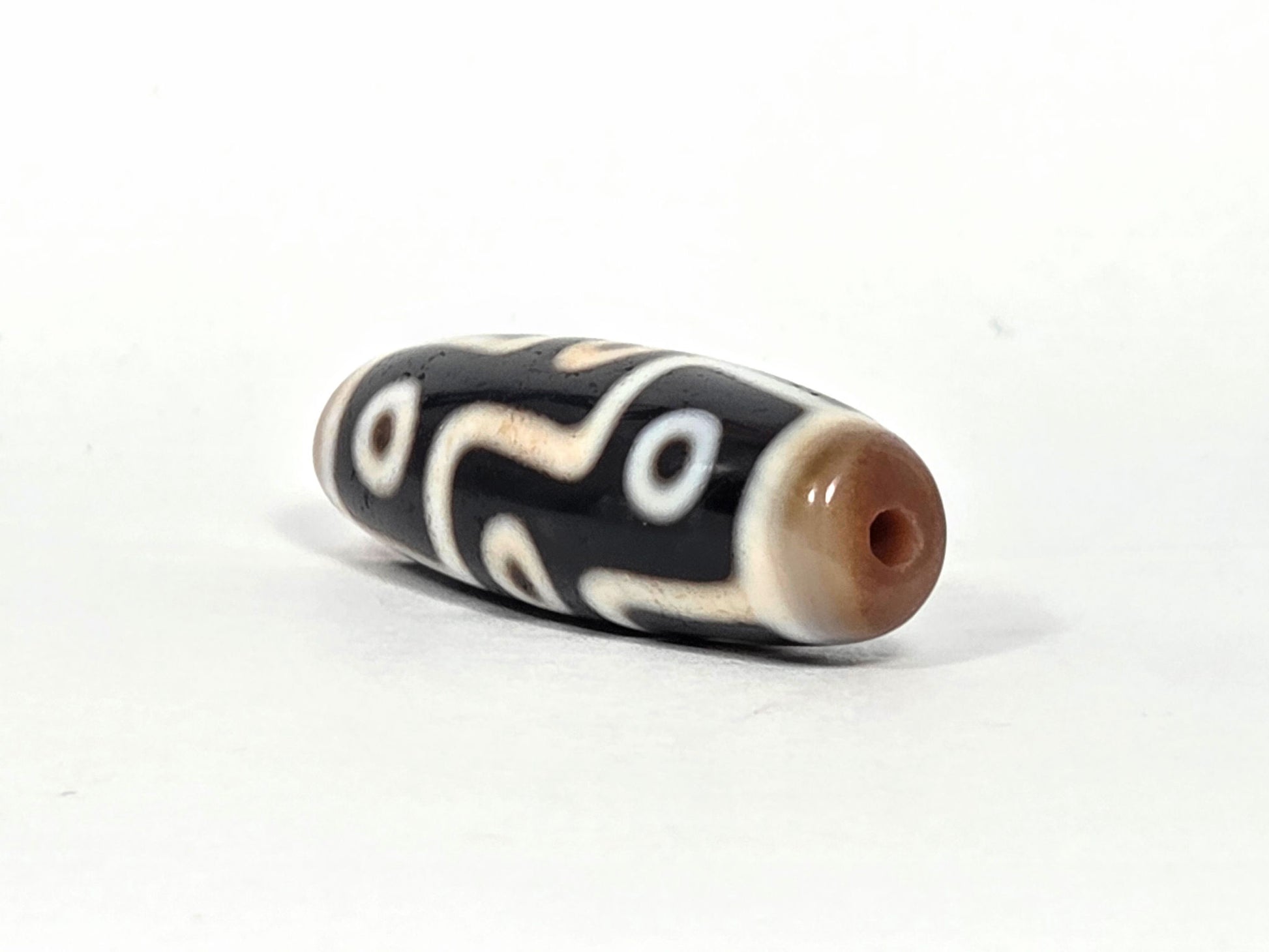 At-070626-9E2 nine eye dzi, angled drill end A, warm medium brown domed cap, small centred hole, pitch-black body, unretouched