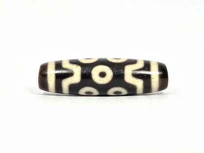 Antique Tibetan seven-eye dzi bead (AT-092826-7E), first lateral profile showing three eyes in upper and lower registers with S-curve wave connectors on deep dark brown-black agate, 39.7 mm, 200–400 years old