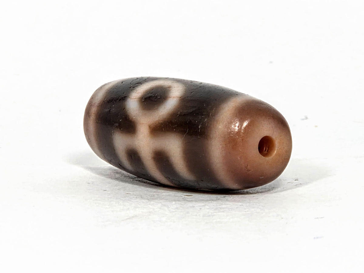 V-071426-BNF end angle B — opposite warm end cap, eye and descending motif elements visible, unretouched.