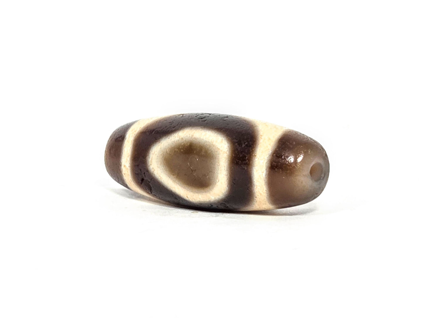 V-071126-HE three-quarter end, dark brown end cap no cream zone, small drill hole, teardrop oval visible on body, unretouched