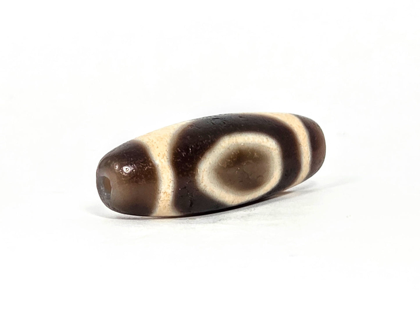 V-071126-HE opposite end, dark brown end cap, second drill hole, oval motif with cream enclosing band visible, unretouched