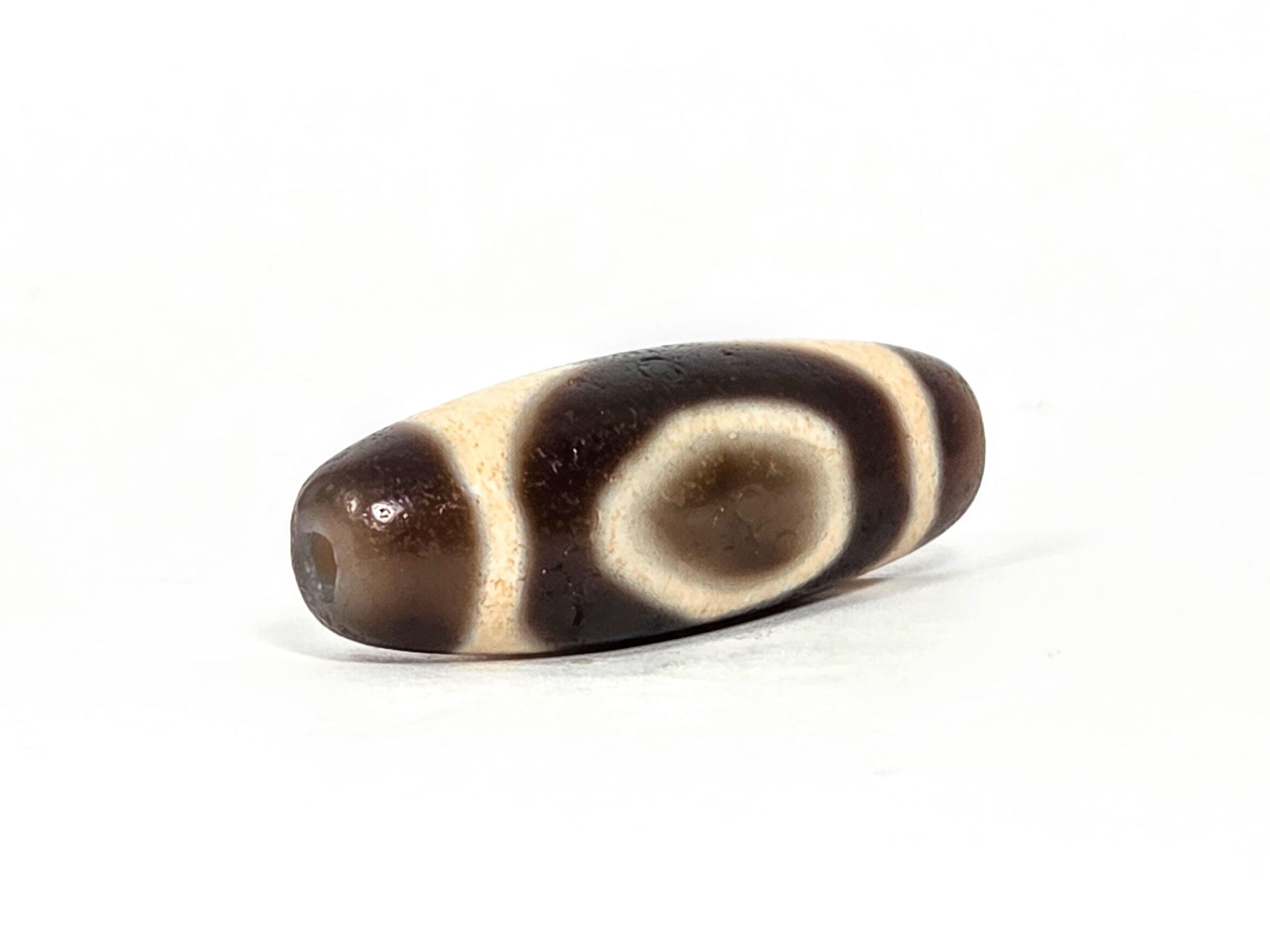V-071126-HE opposite end, dark brown end cap, second drill hole, oval motif with cream enclosing band visible, unretouched