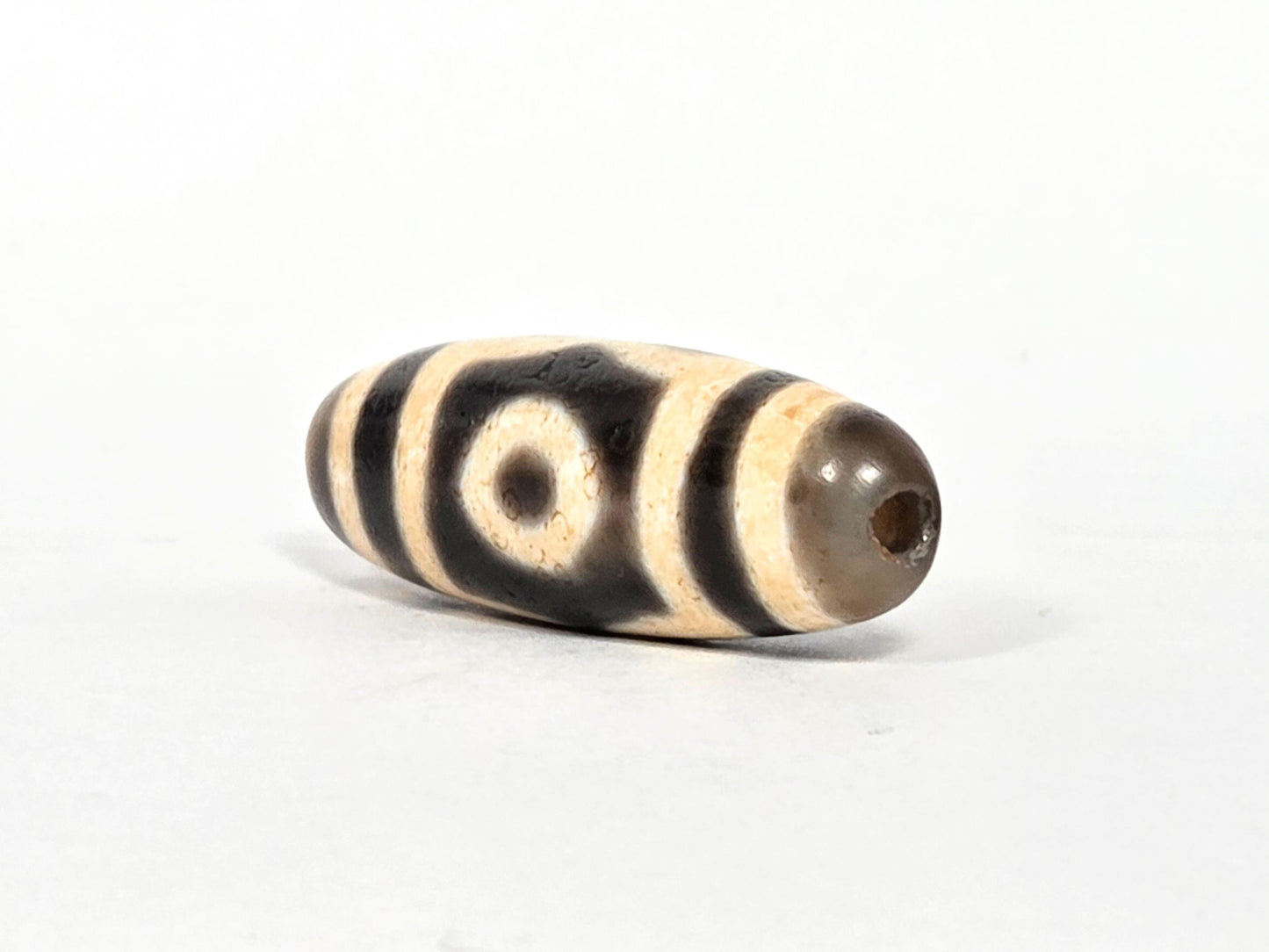 V-071126-3E three-quarter end view, warm grey end cap, small centred drill hole, one eye visible on body, unretouched